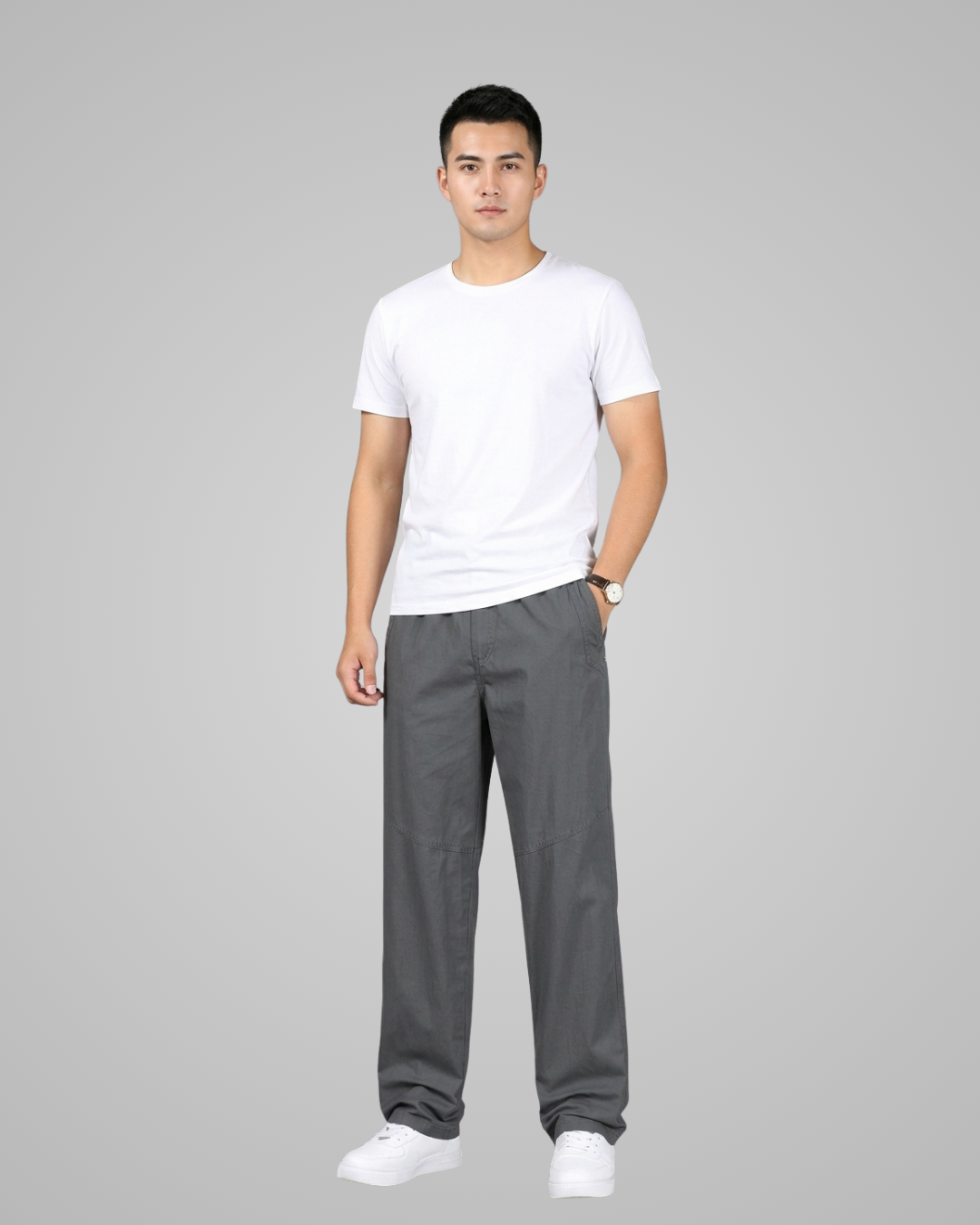 Man wearing a white t-shirt and gray pants on a gray background