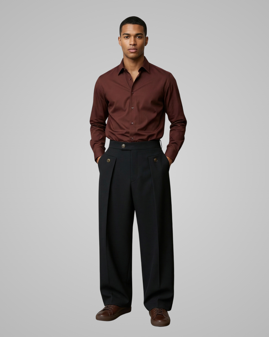 Man wearing a brown dress shirt and black pants against a gray background