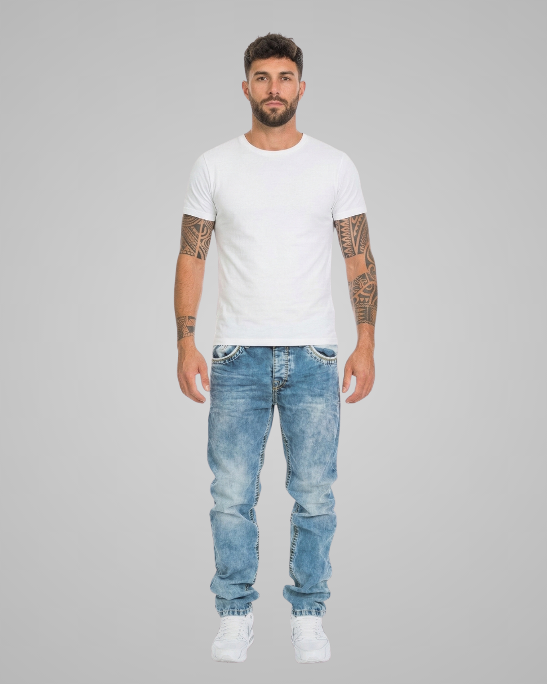 Man wearing a white t-shirt and blue jeans on a gray background