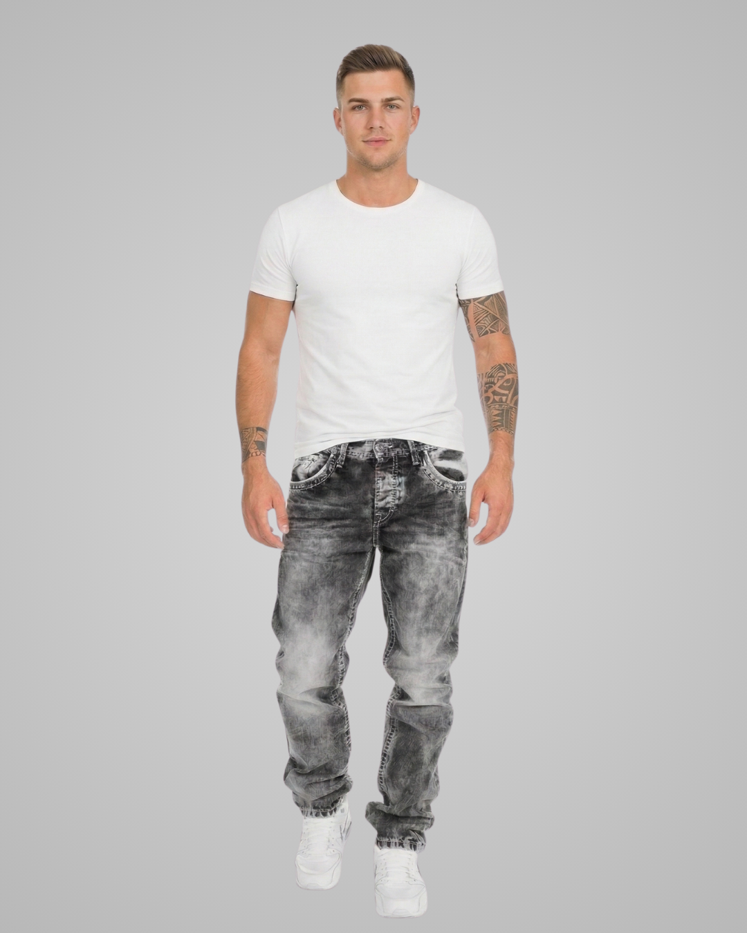 Man wearing a white t-shirt and gray distressed jeans on a gray background