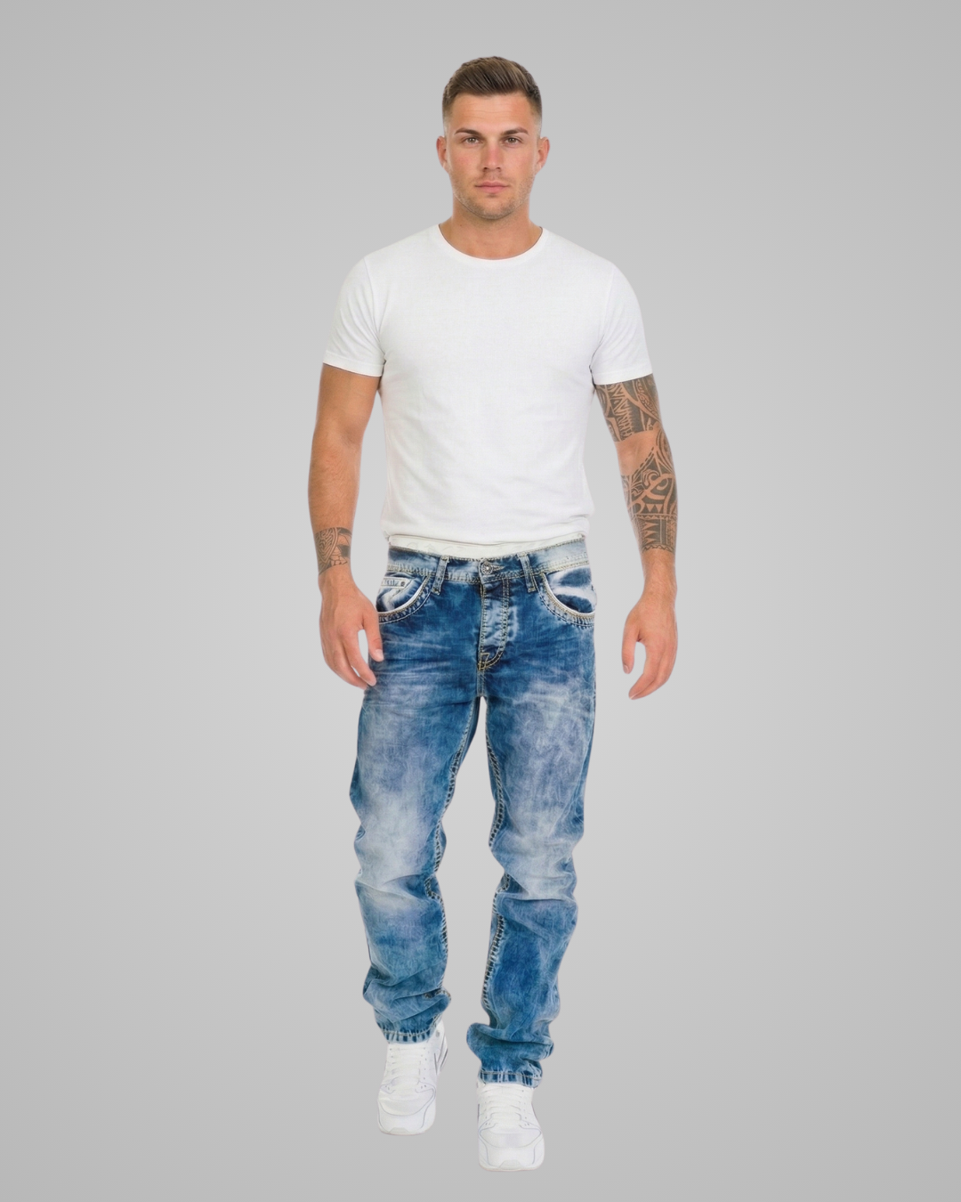 Man wearing a white t-shirt and blue jeans on a gray background