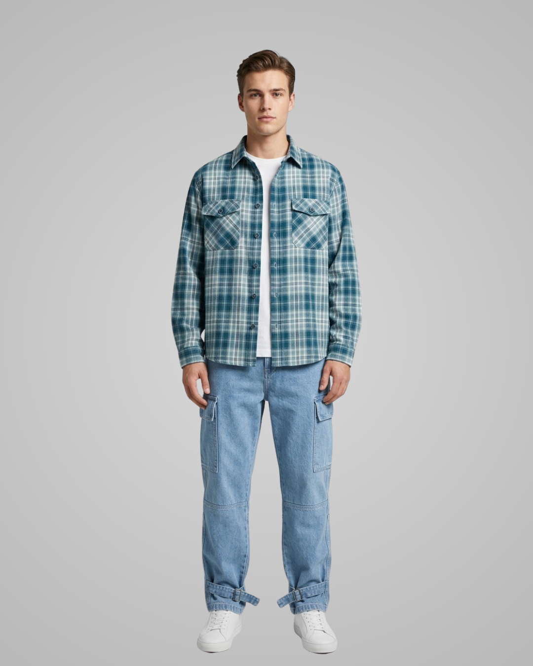Man wearing a blue plaid shirt and jeans on a gray background