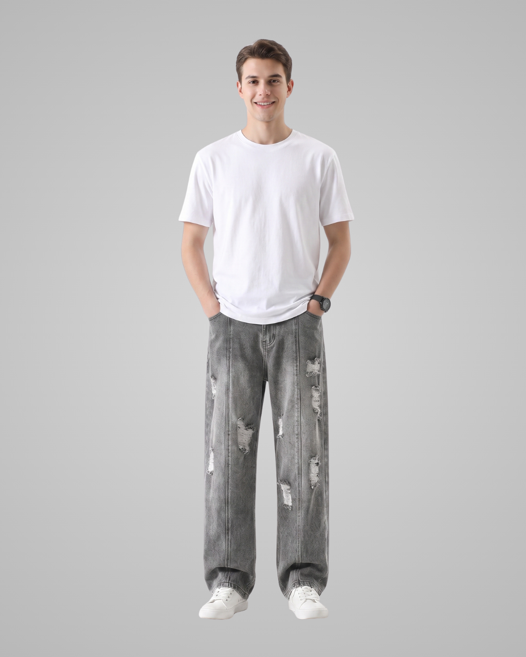 A young man standing against a solid gray background, wearing a plain white crew-neck t-shirt, distressed gray jeans, and white sneakers.