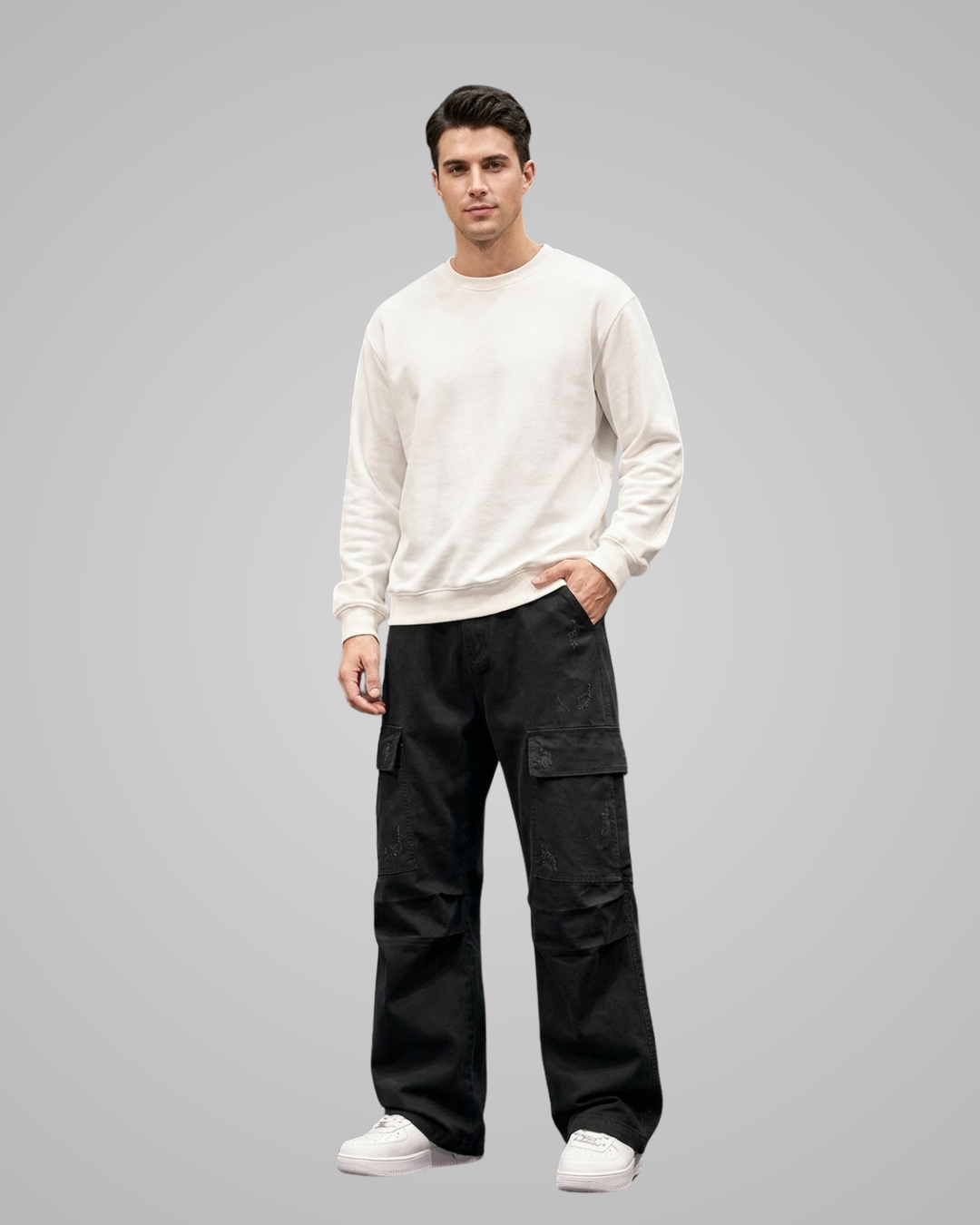Man wearing a white sweater and black cargo pants on a gray background