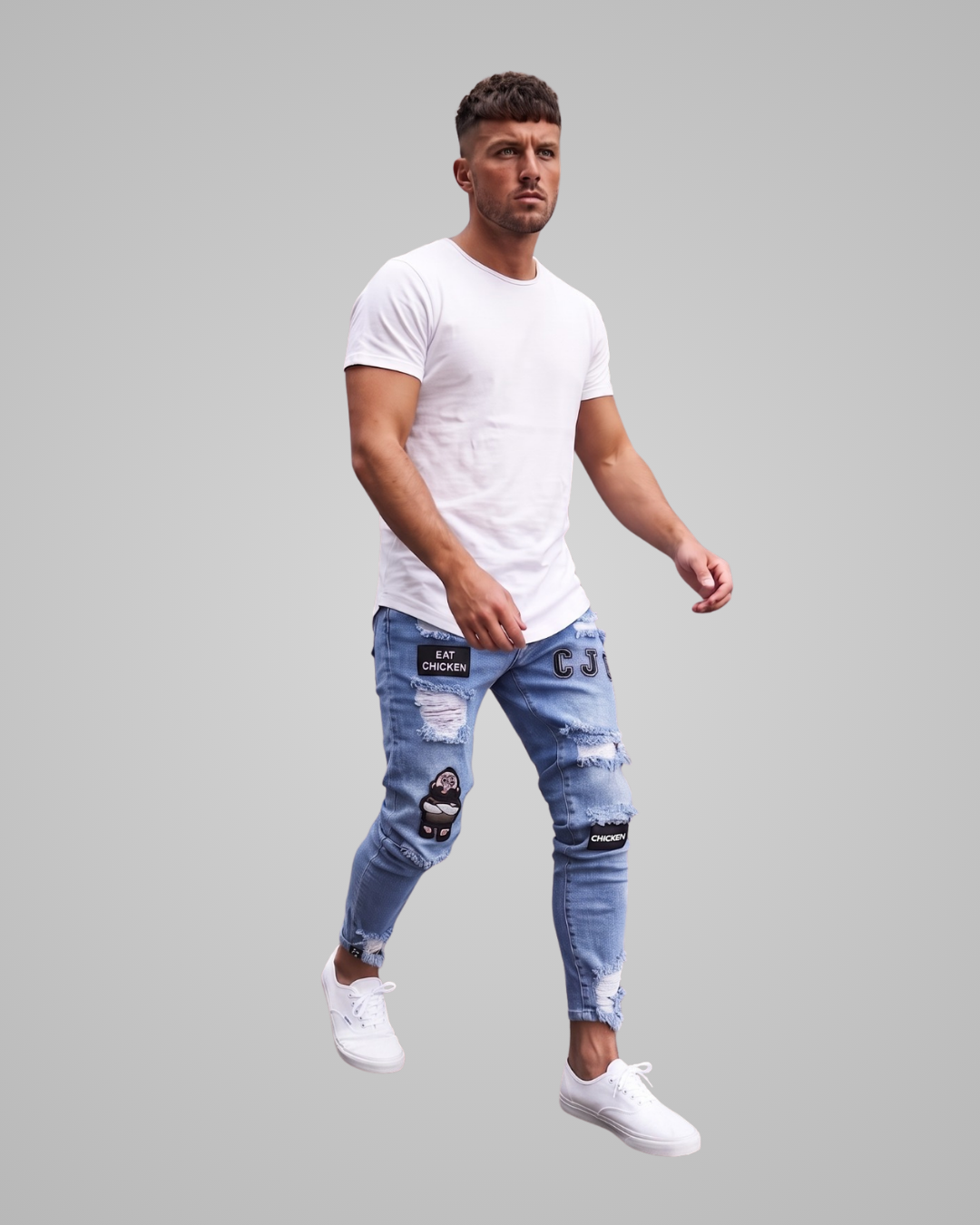 A man wearing a white crew-neck t-shirt, light-wash distressed blue jeans with knee patches, and white sneakers, captured mid-step against a solid gray background.