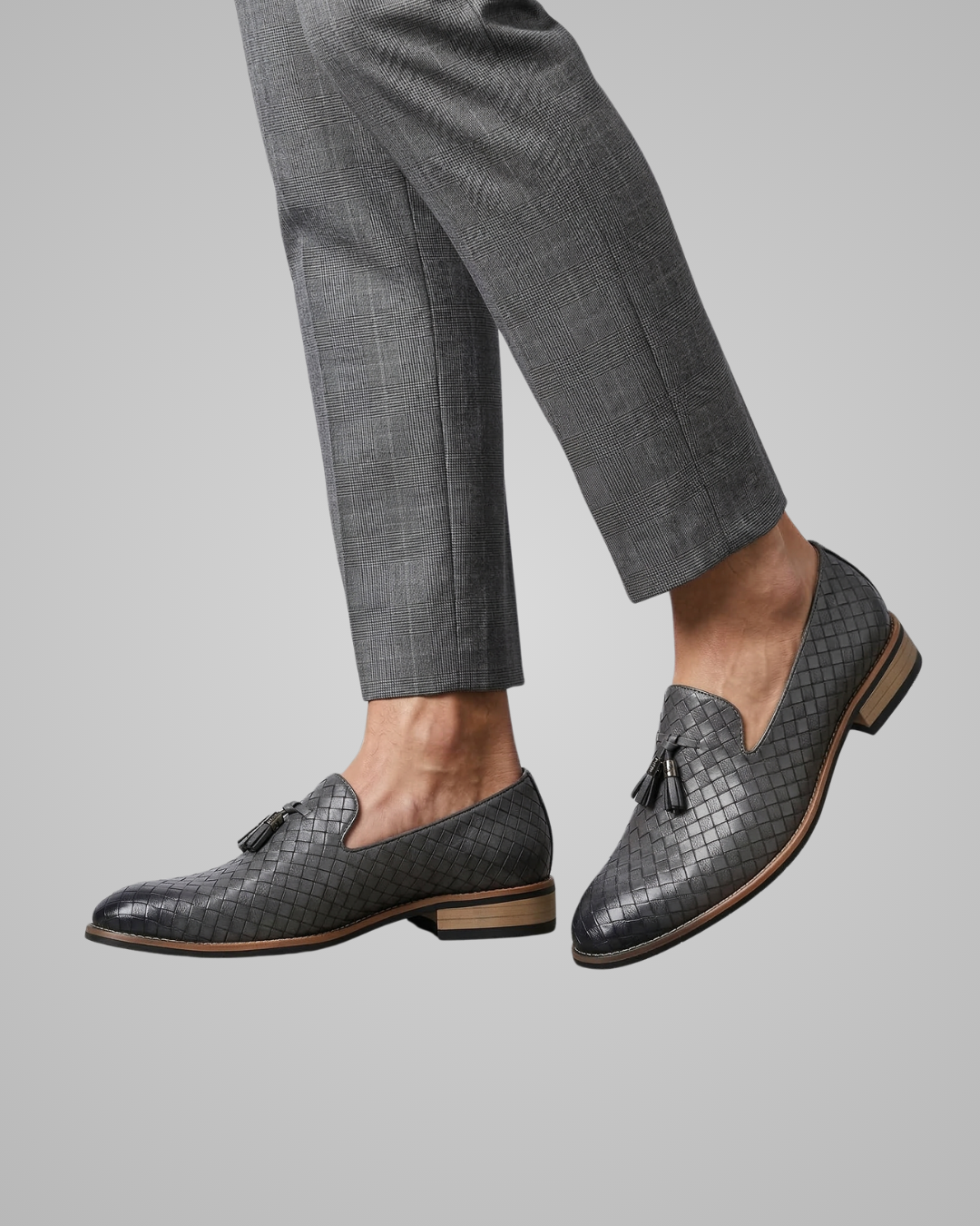 Gray textured loafers worn with gray pants on a light gray background