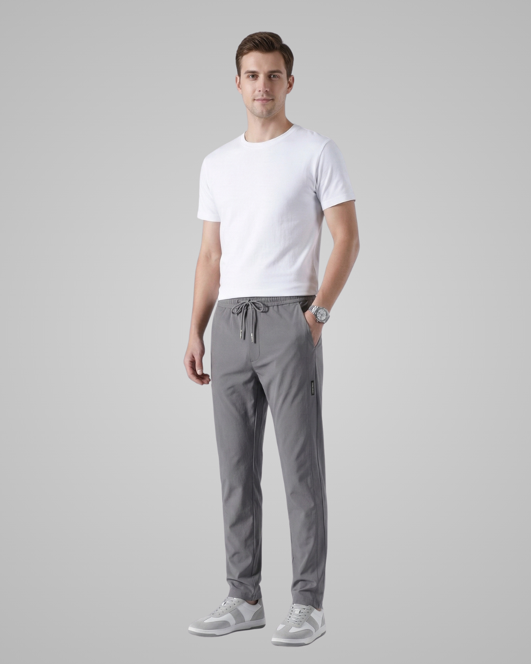 Man wearing a white t-shirt and gray pants on a gray background
