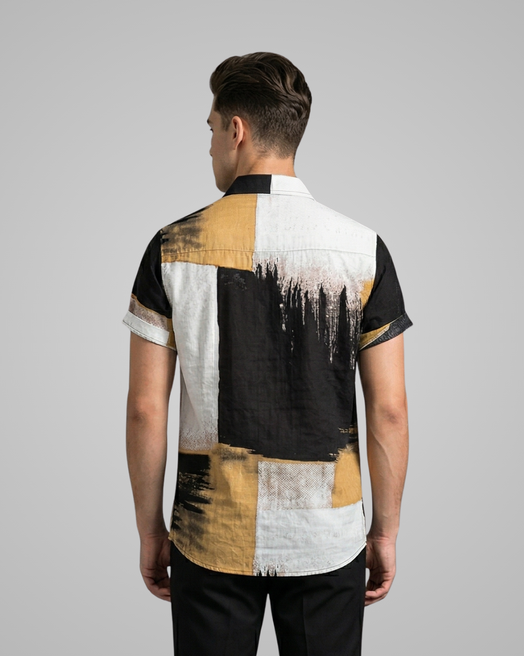 Man wearing a black, white, and mustard yellow patterned shirt on a gray background