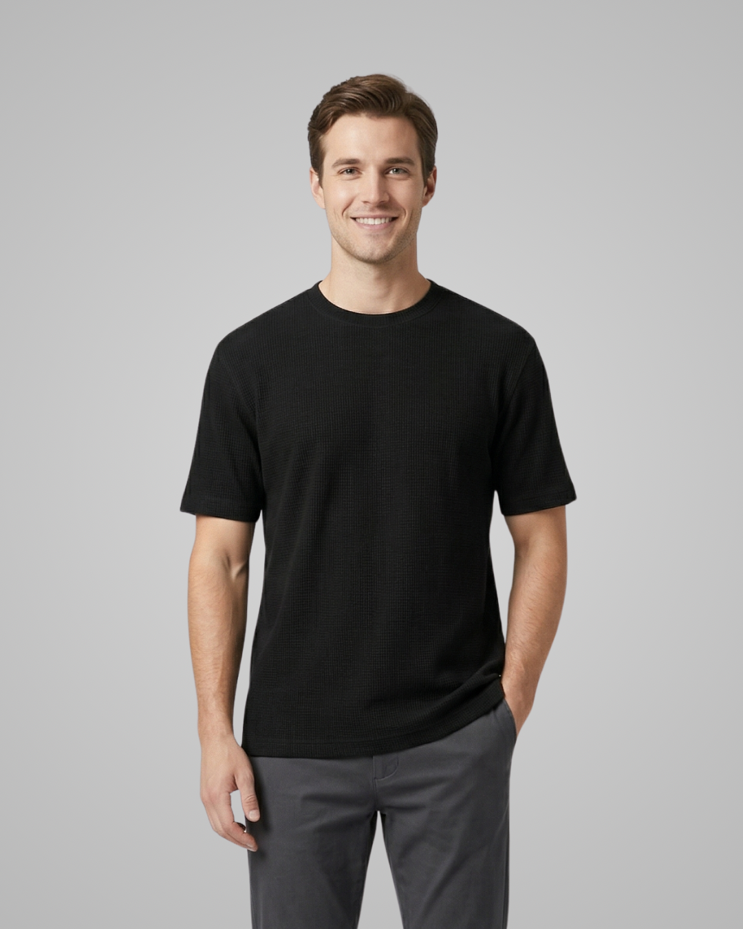 Man wearing a black t-shirt and gray pants on a gray background