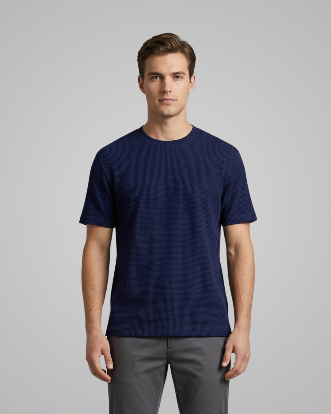 Man wearing a navy blue t-shirt and gray pants on a gray background