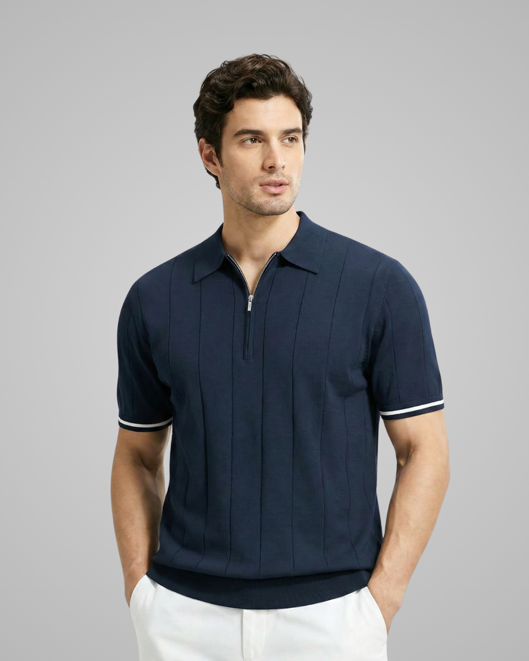 Man wearing a navy polo shirt with white trim on a gray background