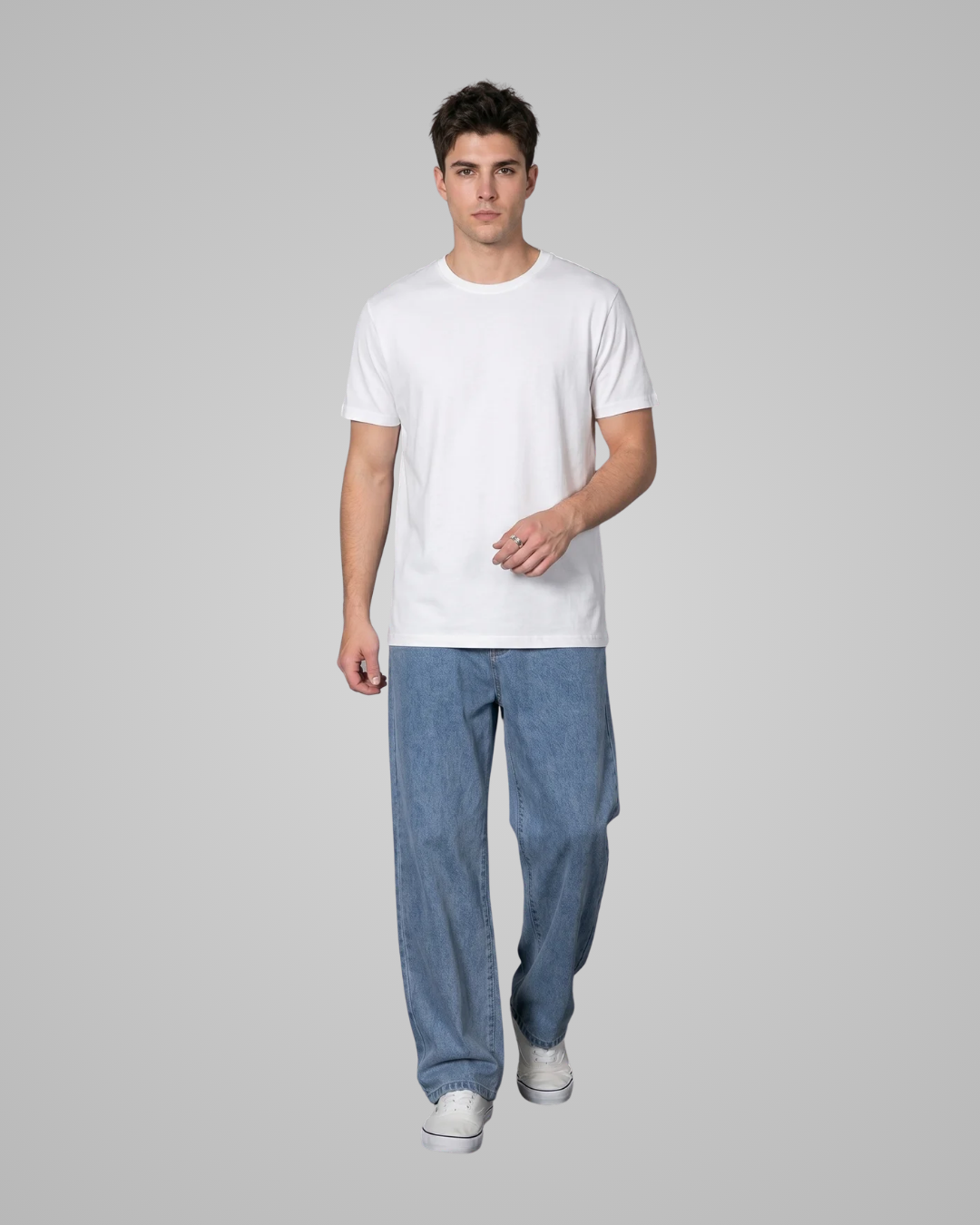 Man wearing a plain white t-shirt and blue jeans on a gray background
