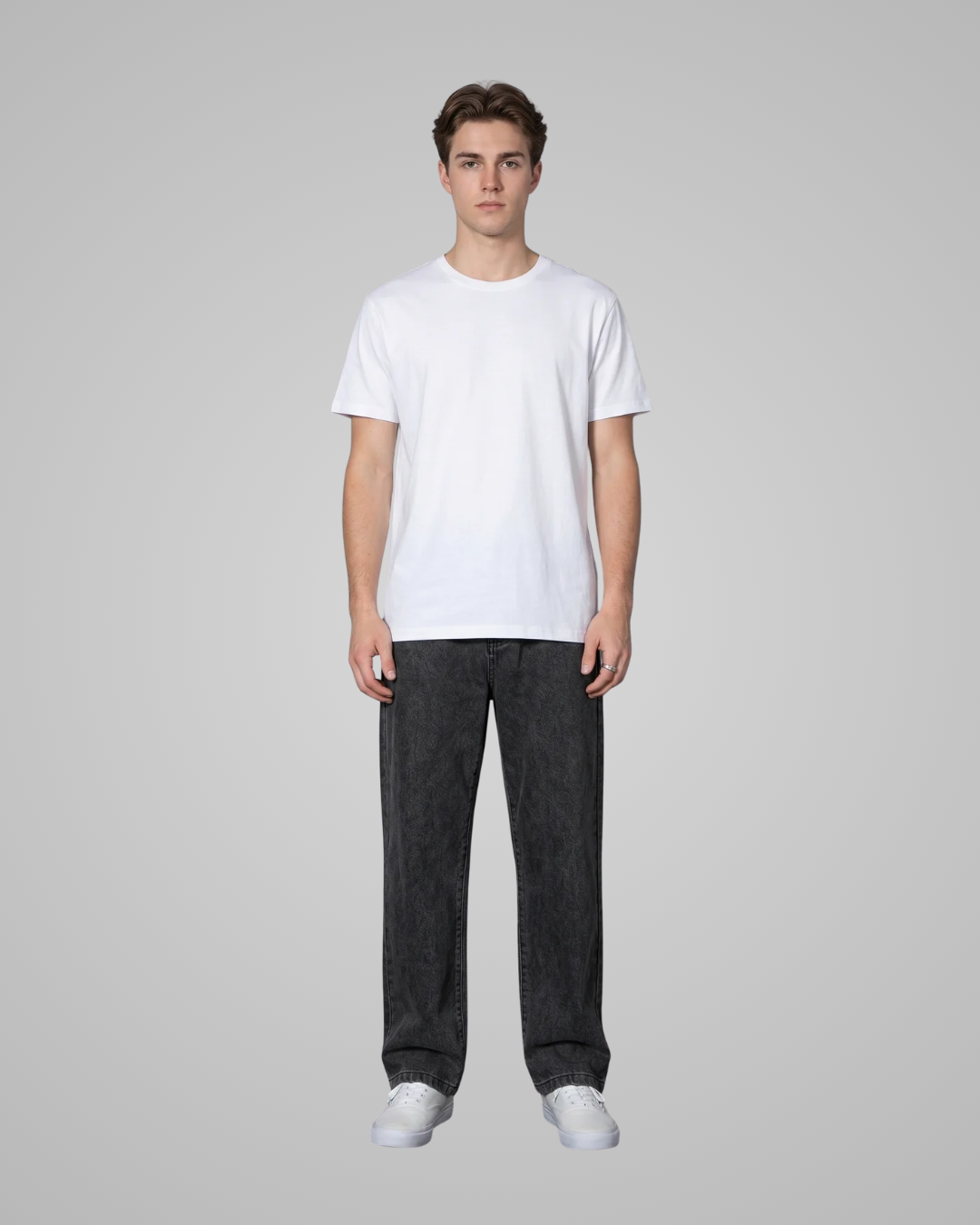 Person wearing a white t-shirt and dark jeans on a gray background