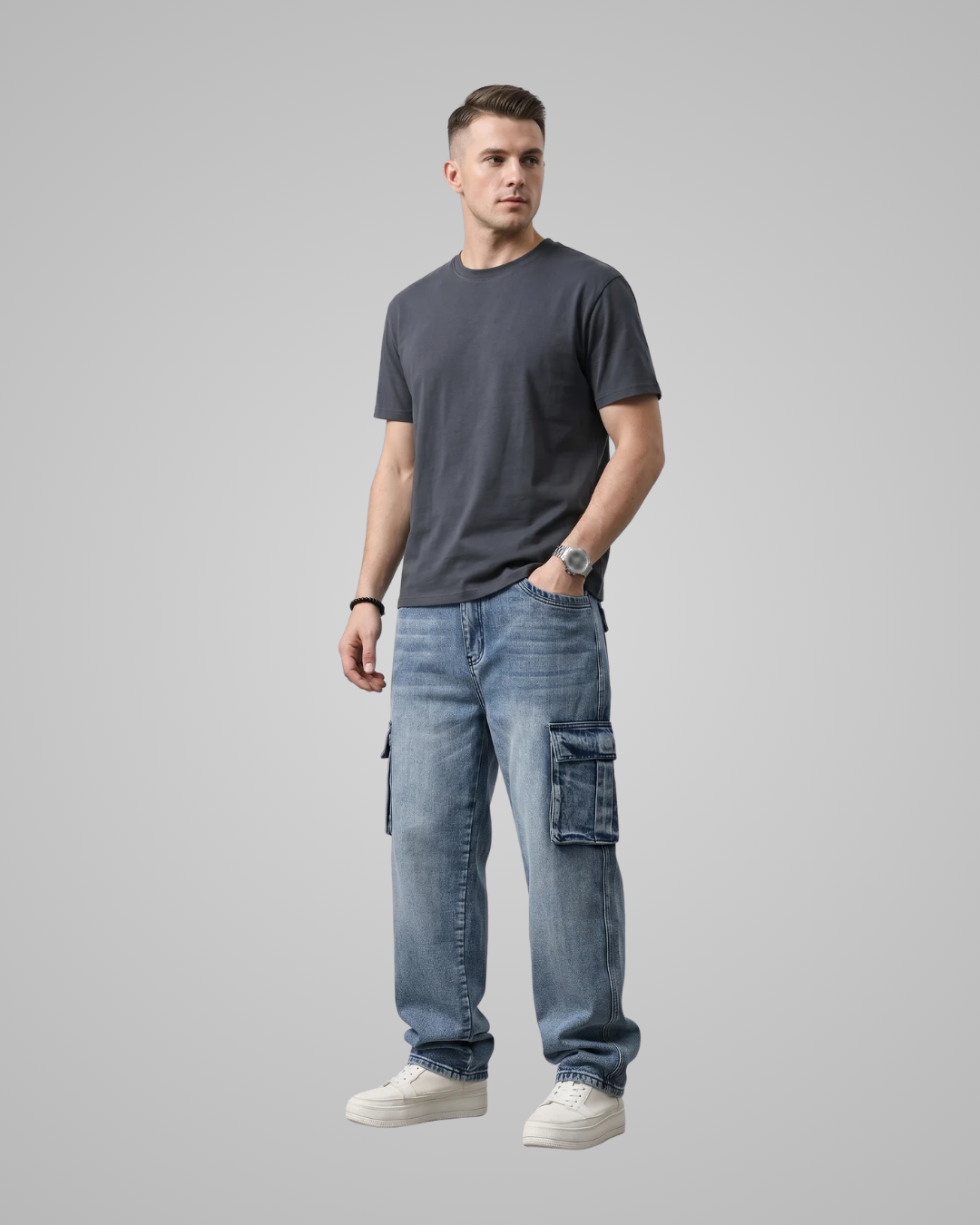 Man wearing a dark gray t-shirt and light blue jeans on a gray background