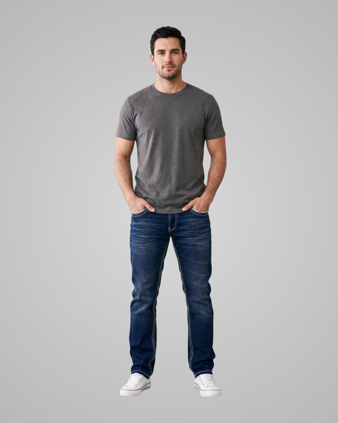 Man wearing a gray t-shirt and blue jeans on a gray background